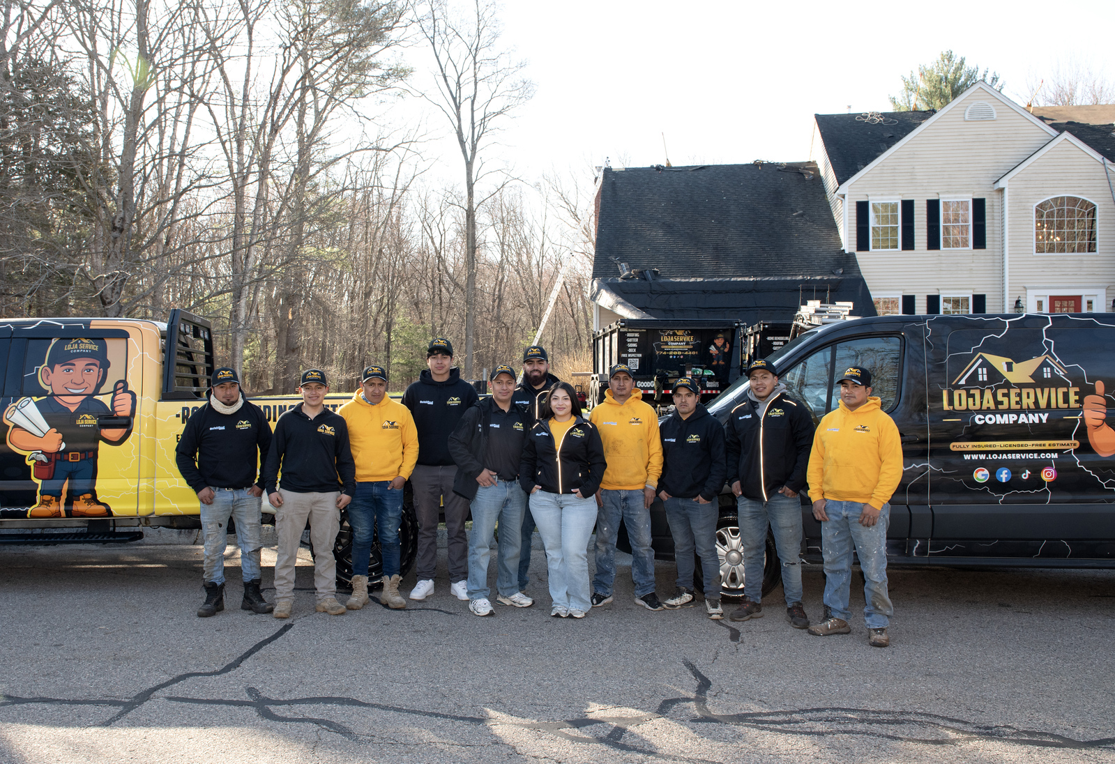 The full Loja Service crew standing in front of company trucks in Massachusetts